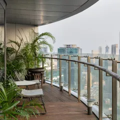 This curved balcony, featured in Polkadot Magazine, offers a panoramic view of the city. The design uses a simple wooden deck and comfortable seating, surrounded by plants, to create a green oasis in the sky.