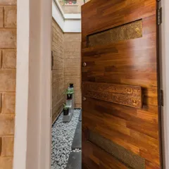Another view of the Vruksha door, opening into a narrow, light-filled passage. The custom handle, made from a reclaimed carved beam, is a centerpiece of the entrance experience.