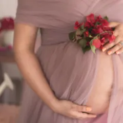 It's all in the details. This close-up shot focuses on the baby bump, draped in soft mauve tulle and adorned with fresh flowers, showcasing the thoughtful details that make each portrait special.