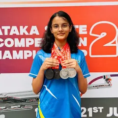A portrait of our champion Indu, showcasing the multiple medals she won at the Karnataka State Shooting Competition through sheer hard work and precision.