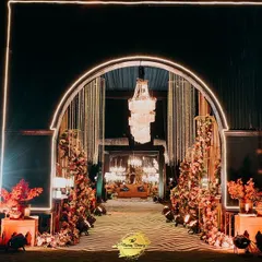A radiant entrance for a night of glamour. This arched gateway, illuminated with warm lights and flanked by intricate decor panels, sets a sophisticated tone for an unforgettable cocktail or sangeet evening.