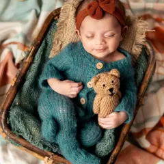 A sweet newborn girl in a cozy knit outfit, cuddling her tiny teddy bear. I have a variety of adorable outfits and props to add a touch of personality to your session.