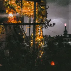 A perfectly timed photo capturing a flash of lightning behind the garden. It shows the dramatic beauty of nature against the calm, steady glow of the garden lights.