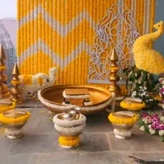 A beautiful Haldi ceremony setup with a marigold and jasmine flower backdrop. The decor also features a peacock and elephant made of flowers.