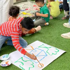 I love providing a space for unstructured creativity. This young artist is painting freely on a large canvas, while others in the background enjoy the sand pit. It’s all about joyful, messy, and memorable play.