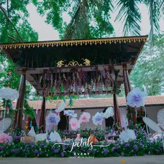 A whimsical Mehendi setup at The Tamarind Tree, featuring a pastel color palette. The decor includes large, handmade organza flowers and hanging origami birds, creating a dreamy and artistic atmosphere.