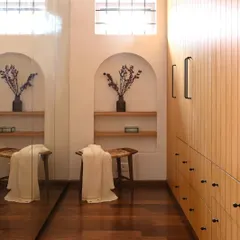 A peek inside the custom walk-in closet I designed for the master bedroom. The light wood cabinetry with minimalist black hardware provides ample storage, while the arched niche adds a decorative touch that ties back to the home's Spanish-inspired architecture.