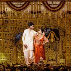 A grand stage photo from a Pondicherry wedding, with the couple framed by an elaborate, traditional golden backdrop.