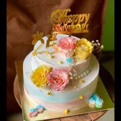 A beautiful two-tier cake for a 25th anniversary. I used a pastel watercolor buttercream effect and decorated it with fresh roses and a "Happy Anniversary" topper.