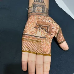 The design in progress, with the checkerboard (jaali) pattern being filled in around the central peacock motif.