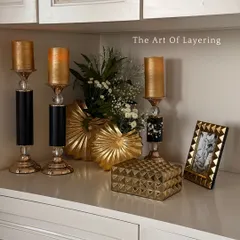 The art of layering, demonstrated with our golden candle holders, decorative boxes, and a photo frame. We believe it’s not just what you place, but how you place it that tells a story of elegance.
