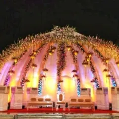 A magnificent dome-shaped stage structure for a grand reception, fully decorated with flowers and intricate lighting, creating a royal look.