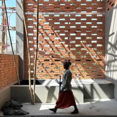 A worker walks past a newly constructed brick screen at our Alibaug site. The image captures the beautiful way sunlight filters through the perforations, turning a simple wall into an interactive surface.