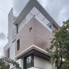 The angular composition of this facade combines wood-look cladding and white planes, with a slatted pergola on the roof adding texture and filtering sunlight.
