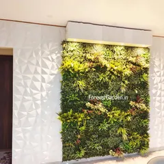 An interior green wall installation featuring built-in uplighting that highlights the rich textures of the foliage. This design adds a touch of luxury and drama to the living space.