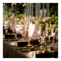 A close up of a sophisticated table setting for a formal birthday dinner. The combination of classic white and gold dinnerware, crystal glassware, and soft candlelight reflects our attention to detail in creating a refined ambiance.