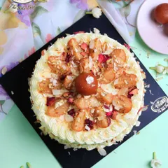 An overhead view of our stunning Gulab Jamun Cake. This eggless cake is adorned with soft gulab jamun pieces, toasted almonds, and coconut flakes, making it a centerpiece for any celebration.