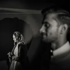 A creative portrait where love is painted with light and shadow. The groom's silhouette creates a powerful frame for his bride, showcasing an artistic and modern approach to wedding photography that tells a deeper story.