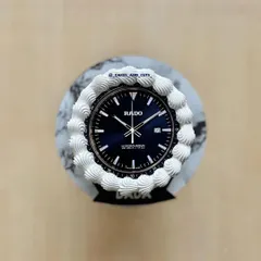 A top-down view of the RADO watch cake, showing the detailed watch face and buttercream piping.