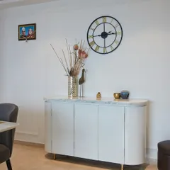 This contemporary sideboard with a marble top and clean, modern design is styled with a large wall clock and decorative items for a minimal yet chic appeal.