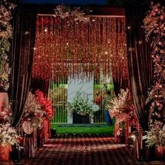 A dramatic and glamorous entrance for a night reception. A cascade of shimmering gold strings hangs between dark drapes, leading guests into the main event space with a sense of grandeur.