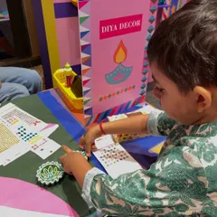 Look at the focus on this little one's face. Using sticker sheets is a fantastic, mess-free way for toddlers to participate in diya decoration and feel a great sense of accomplishment.