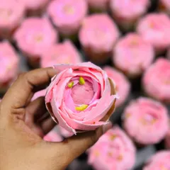 A close-up of a single Rose Rasmalai cupcake, showing the detailed piping work that creates the rose petal effect. It's a perfect blend of Indian dessert flavors and classic cupcake form.