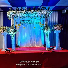 A classic mandap structure decorated with white flowers and blue drapes. This versatile setup can be used for various pujas and religious ceremonies in a hall or at home.