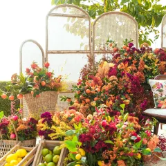 A vibrant and bountiful Haldi setup in Udaipur, as featured by WeddingSutra. The seating area is surrounded by an abundance of flowers in shades of red, orange, and yellow, with fresh lemons and limes in baskets adding a citrusy touch.