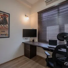 A simple and effective home office setup with a long desk providing ample workspace. The vintage poster adds a touch of personality to the functional design.