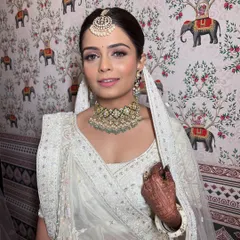 A close-up portrait showing the soft, blended makeup that complements her white outfit and polki jewelry perfectly.