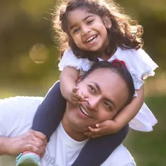 A close-up of a father-daughter moment from the same family session. The backlighting from the sun adds a beautiful halo effect, highlighting the genuine smiles and connection.