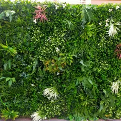 A close-up of the premium artificial green wall from the fashion brand's store. This detailed view highlights the realistic quality and variety of the foliage used, including ferns, ivy, and flowering sprigs.