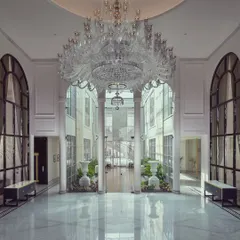 We believe a home's entrance should be a grand statement of what lies within. In this foyer for The Grand Alabaster, a magnificent crystal chandelier descends from a double-height ceiling, reflecting in the polished marble floors. This space was designed to create an unforgettable first impression of opulence and light.