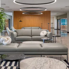 The waiting lounge at Laurus Labs, featuring modern grey sofas and circular pendant lights. We designed this space to be comfortable and sophisticated, using a clean material palette of wood and marble.