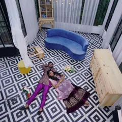 This unique top-down shot captures a fun and intimate moment from a couple's photoshoot. The rich purple ethnic outfits stand out beautifully against the bold, graphic floor pattern.