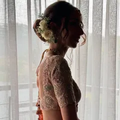 A silhouette of Maansi's delicate and romantic bridal bun. The soft tendrils and the placement of fresh white roses and baby's breath create a look of timeless elegance.