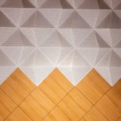 A detail shot of the acoustic wall panels, showing the contrast between the perforated white PET board and the warm laminated plywood below. This combination is not just aesthetic; it is engineered for optimal sound absorption and diffusion.