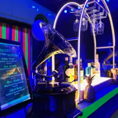 A vintage gramophone serves as a key decor piece on this "Old School" themed bar, blending classic charm with the bright blue neon lighting of the party.