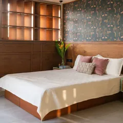 In the primary bedroom of our penthouse, we designed custom wooden screens that function like an art installation. They allow the user to control light, views, and privacy, and are complemented by an elegant Sabyasachi wallpaper.