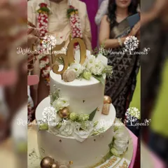 A stunning two-tiered cake for a 50th anniversary celebration. The cake is elegantly decorated with white flowers, gold accents, and a "50" cake topper, symbolizing the golden jubilee.