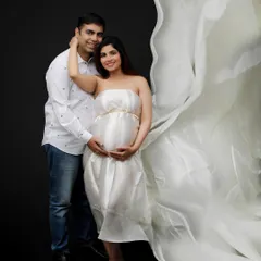 For a touch of modern romance, I love using flowing fabrics and dramatic lighting. This maternity portrait captures the expecting mother in a beautiful white gown, creating an ethereal and goddess-like image against a simple dark background.