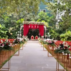 We design the entire ceremony space to be cohesive and beautiful. This wide-angle view shows the red-themed mandap and aisle, lined with floral pedestals, creating a dramatic and elegant path for the couple.