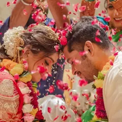 A beautiful candid moment from a wedding ceremony. The bride's intricate hairstyle is visible as she shares a special moment with her groom.