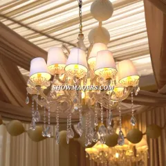 A close-up of a beautiful chandelier used in the outdoor setup. The combination of classic lighting fixtures with draped fabric creates a sophisticated, ballroom-like feel in an open-air setting.