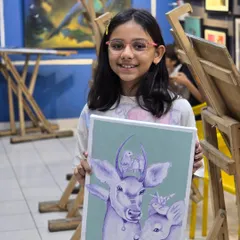 Art is for everyone, and we love seeing our young students thrive. Here, a young student proudly holds her imaginative ballpoint pen drawing of two deer, showcasing her developing skills and creativity.
