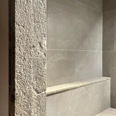 A close-up of a granite pillar at the Polibetta Farmhouse. The rough, hand-finished texture of the stone provides a tactile experience and contrasts with the smooth polished granite used elsewhere.