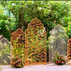 This Haldi backdrop features modern, arch-shaped panels decorated with strings of marigolds and tuberoses. It's a fresh and contemporary take on traditional Haldi decor.