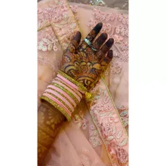 A close-up of a gorgeous, dark peacock feather mehndi stain, paired with pink bridal bangles. The contrast really makes the deep color of the henna pop.