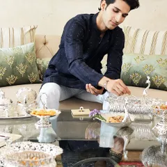 Here, a guest enjoys the elegance of my silver-plated serveware. The intricate peacock and elephant motifs on the bowls and trays are designed to make hosting feel effortless and every celebration special.